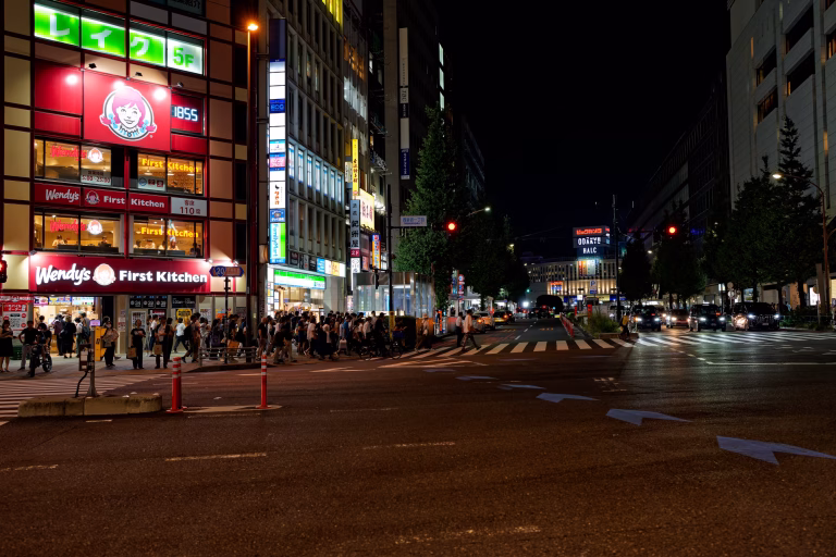Night time street intersection in Shinjuku with pedestrians and illuminated storefronts