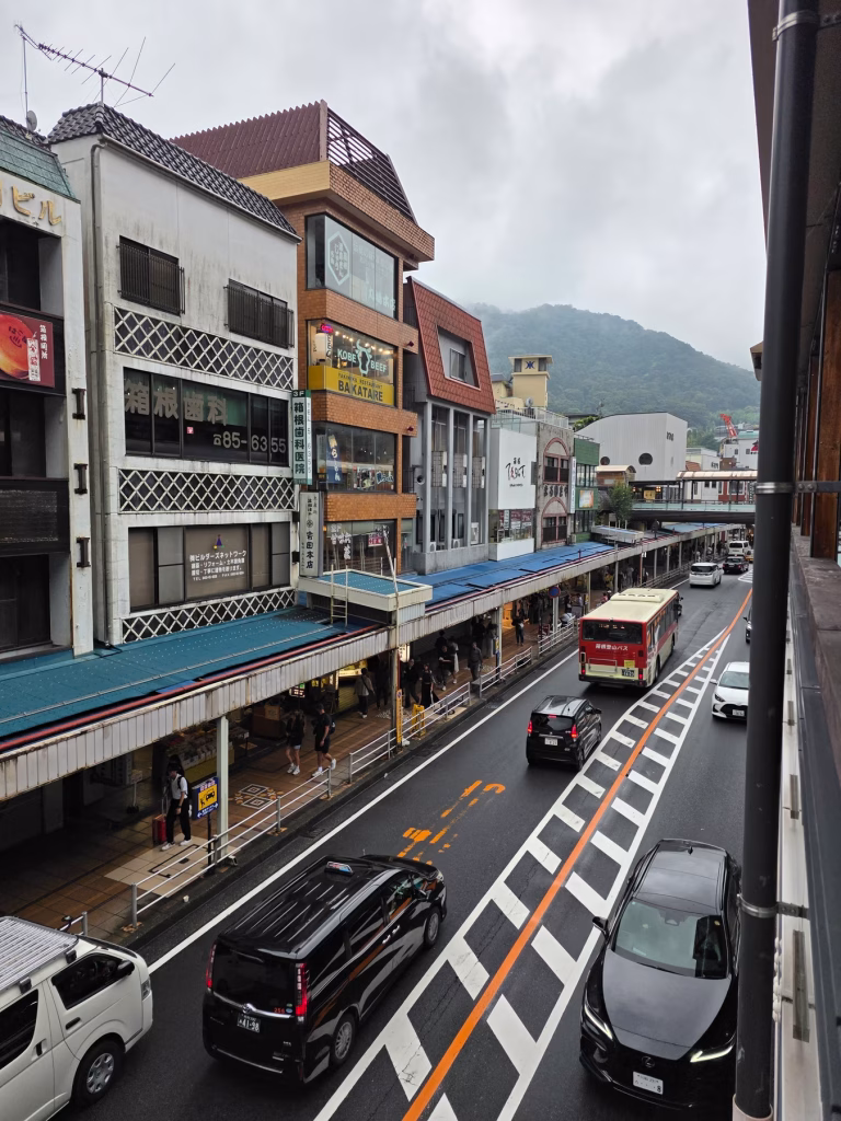 Quiet street in Hakone with local storefronts, light pedestrian traffic and overcast skies.