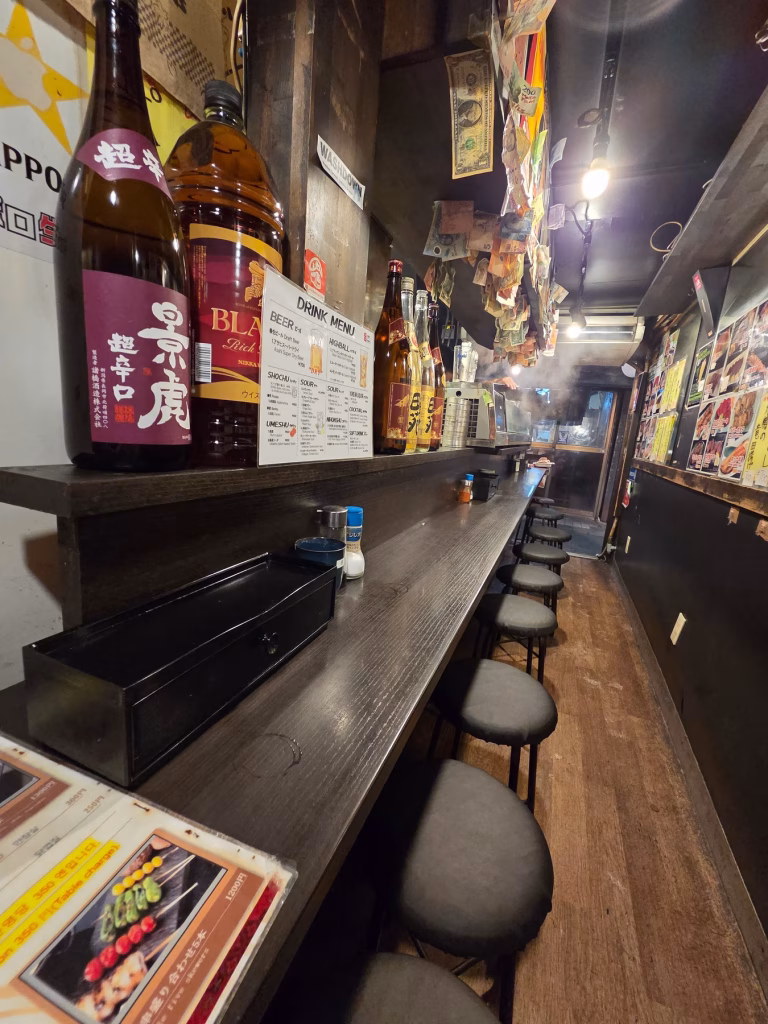 Small izakaya bar with sake bottles in Omoide Yokocho, Shinjuku